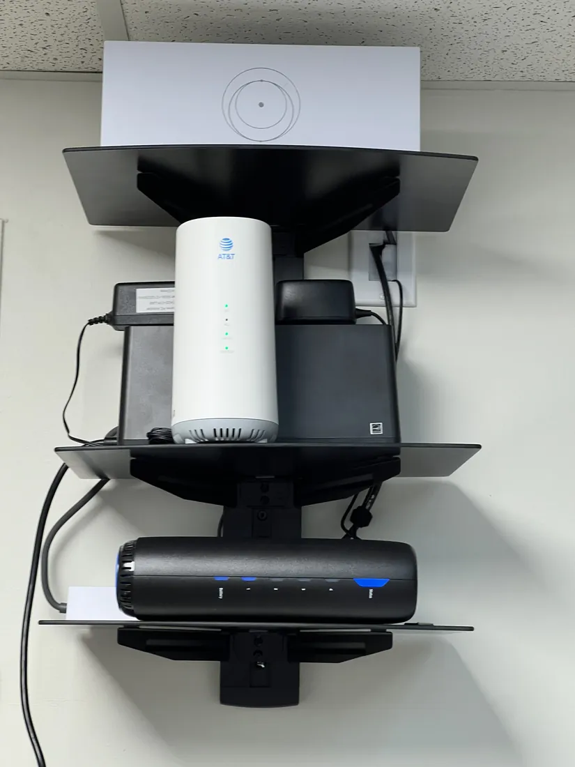 Clean, organized, wall-mounted networking equipment on a UPS battery backup after cleanup