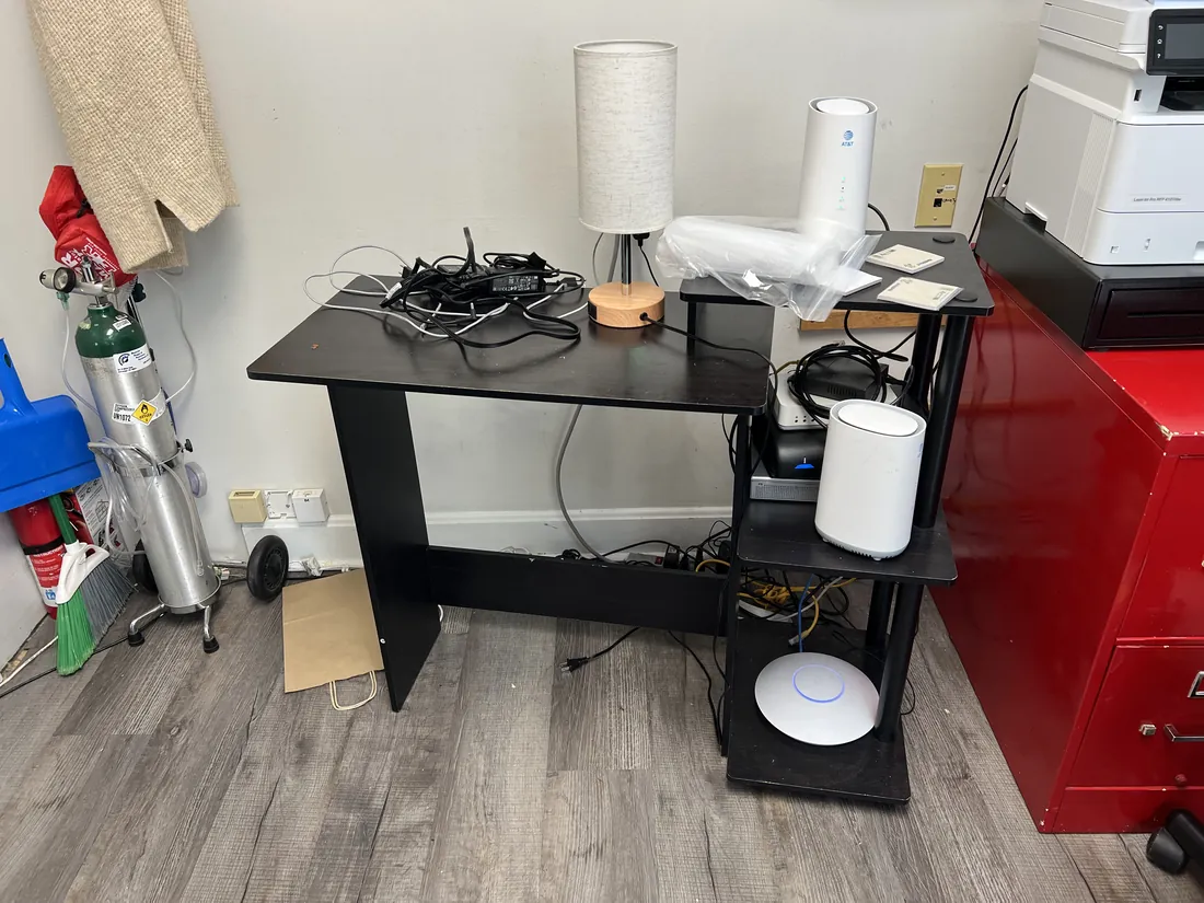 Tangled cabling and networking equipment piled on a desk before cleanup